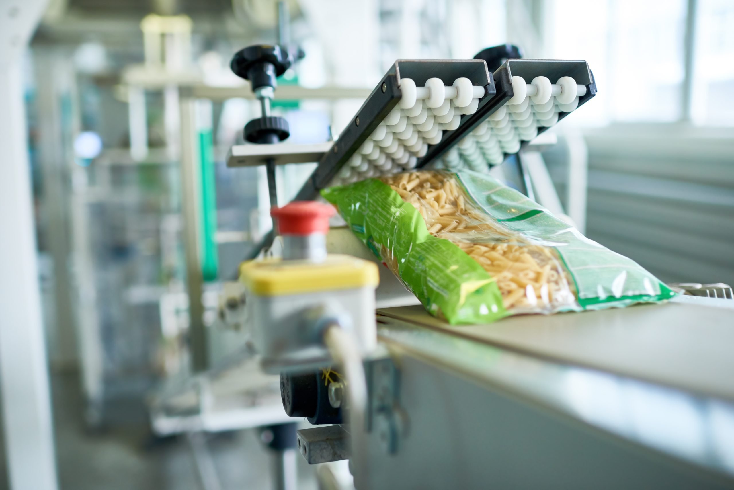 Close up of production process at modern food factory, focus on macaroni bag ready for packaging sliding down assembly line, copy space. PAR4012 Series Spec Sheet | Ultrasonic Transducers Use in Packaging | Parsonicscorp.com | 815.338.6509